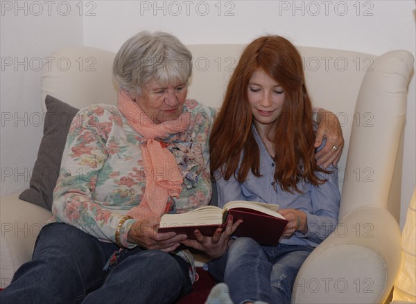 Granddaughter and grandmother reading a book together