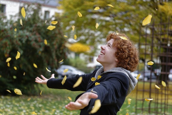 Teenager throwing autumn leaves