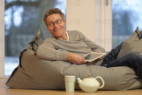 Man lying on large pillow with tablet