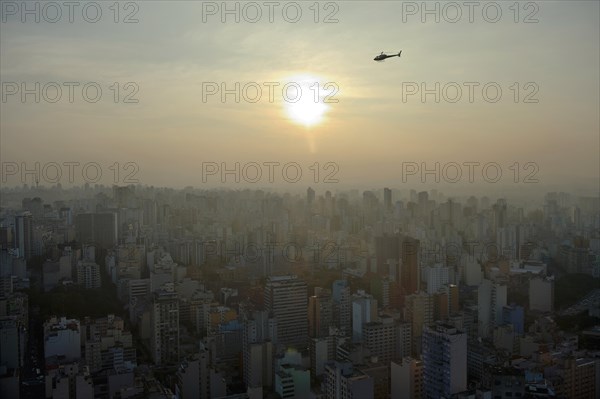 Helicopter above a cityscape with skyscrapers at sunset