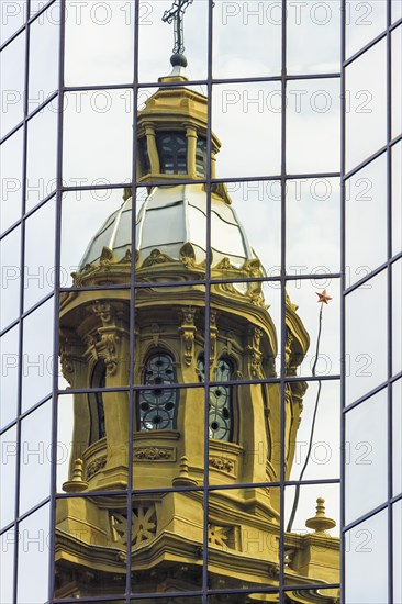 Cathedral tower reflecting in a glass building