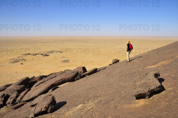 Man looking from Aicha monolith towards the flat desert