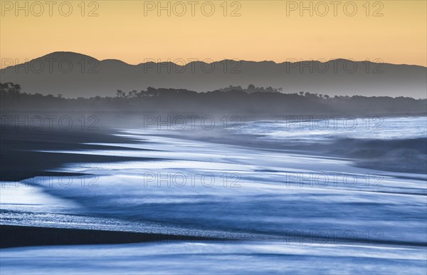 Surf with haze on a wide beach in the evening light