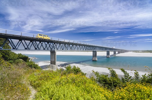 Yellow car driving over Haast River Bridge