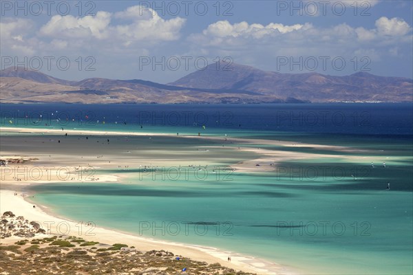 Beach and turquoise sea with windsurfers