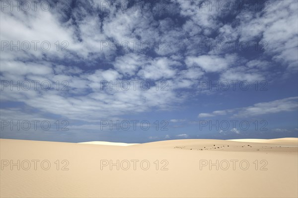 Sand dunes under blue sky with clouds