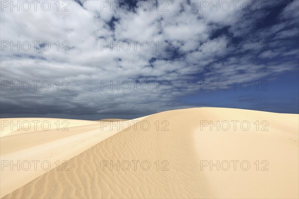 Sand dunes under blue sky with clouds