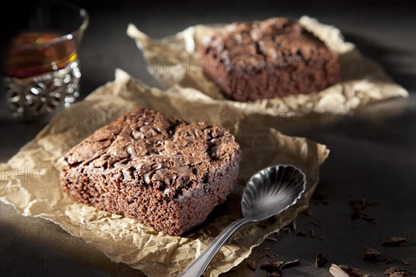 Two brownies with chocolate sauce on paper with spoon and tea