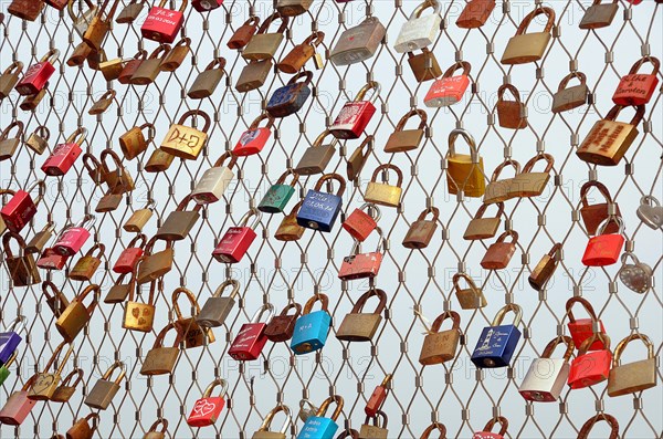 Love locks hanging on metal grid