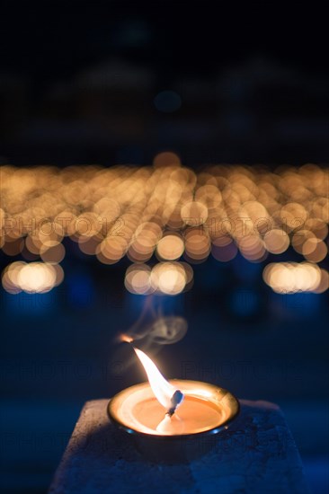 Burning candle with many lights in the background