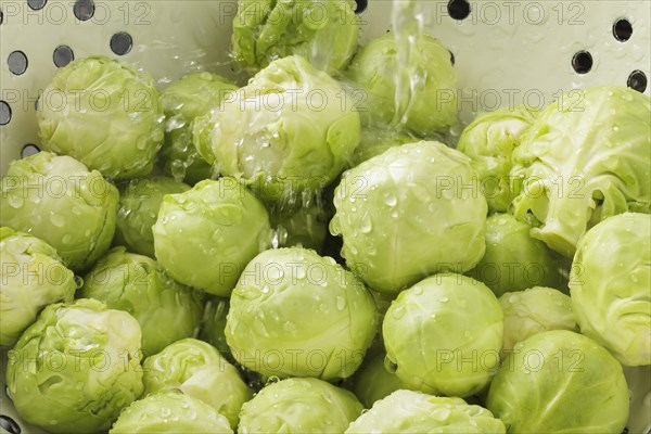 Brussels Sprouts in colander with running water