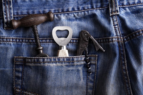 Old corkscrew and bottle openers in the pocket of jeans