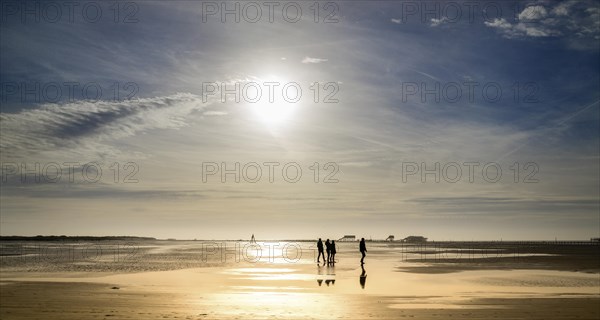 Walkers on the beach at sunset