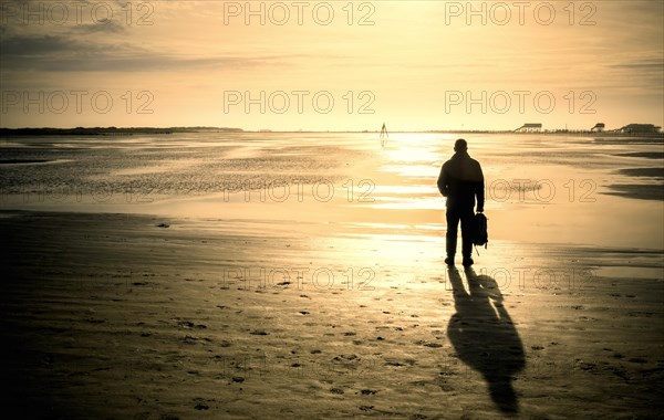 Walker on the beach at sunset