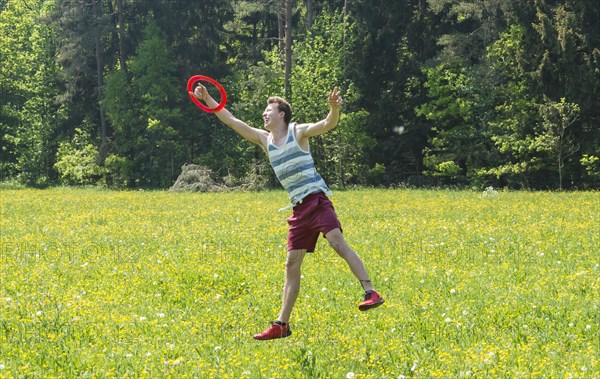 Young man catching frisbee in meadow