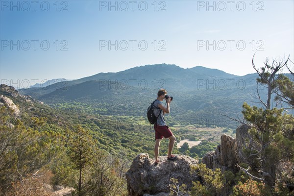 Young man doing landscape photography of the mountainous views in Sartene