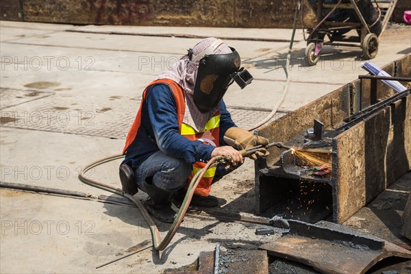 Worker welding steel beam on construction site