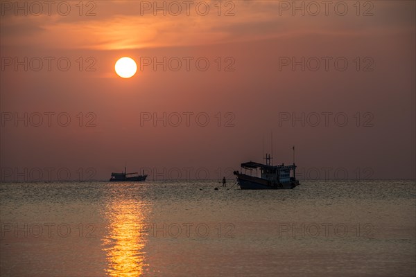 Boats in sea at sunset