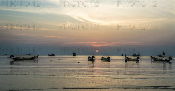 Long-tail boats in sea at sunset