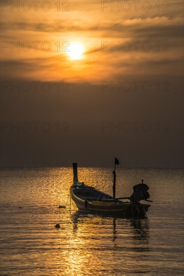Long-tail boat in sea at sunset