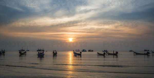 Long-tail boats in sea at sunset