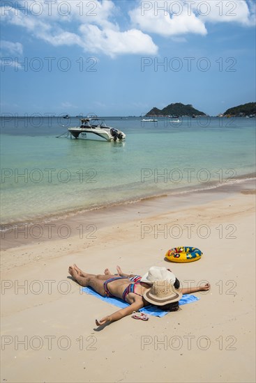 Mother and child lying on sandy beach