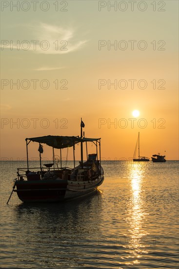 Fishing boat in sea at sunset