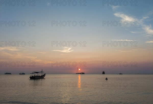 Boats in sea at sunset