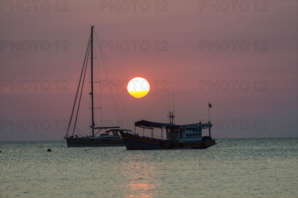 Two boats in sea at sunset