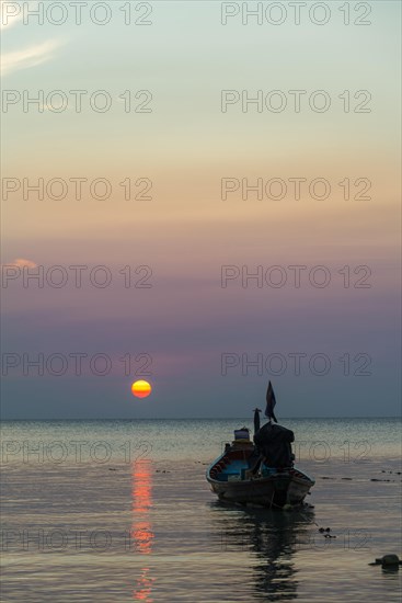 Long-tail boat in sea at sunset