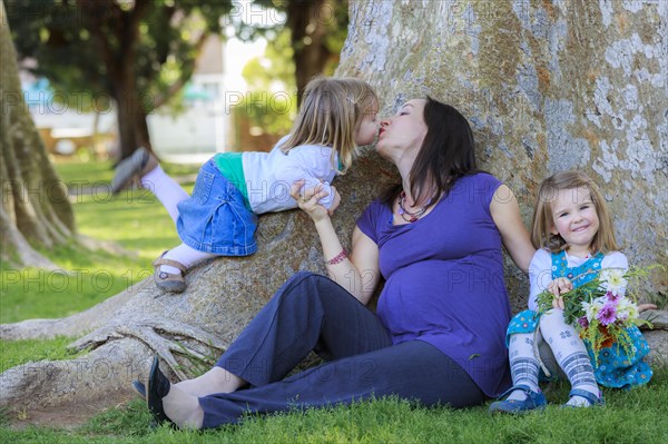 Pregnant woman in the park with her daughters