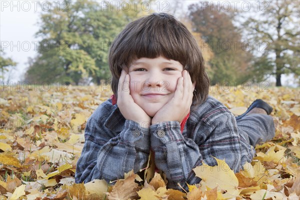 Little boy lying in autumn leaves