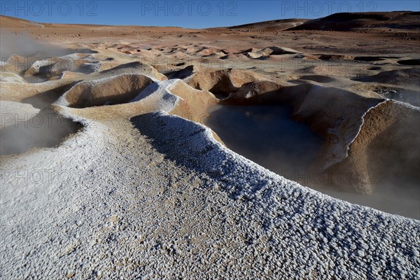 Geysers with water vapor frozen into ice flowers at edge