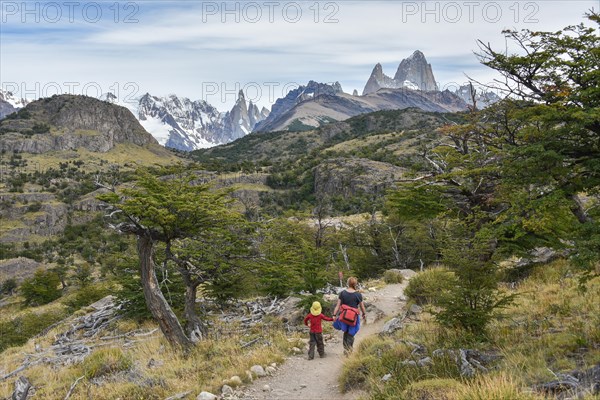 Young woman and young boy hiking in front of mountain range with Monte Fitz Roy near El Chalten