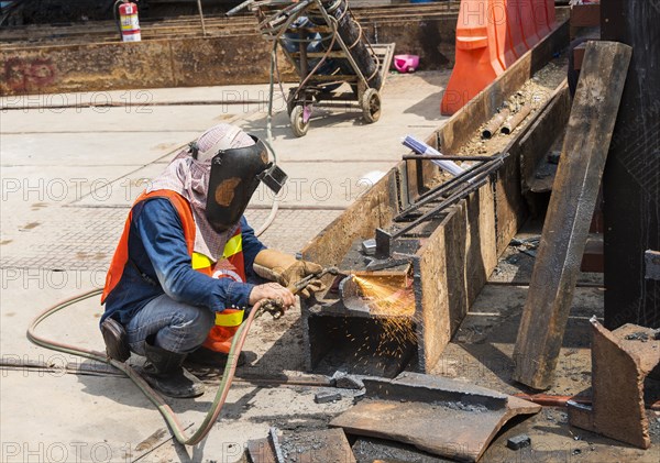 Construction worker welding a steel beam on a construction site