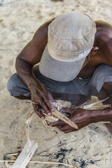 Man of the Orang Asil starting a fire