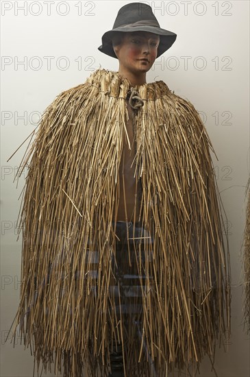 Figure of a shepherd boy with Franconian weather protection made from straw in a showcase