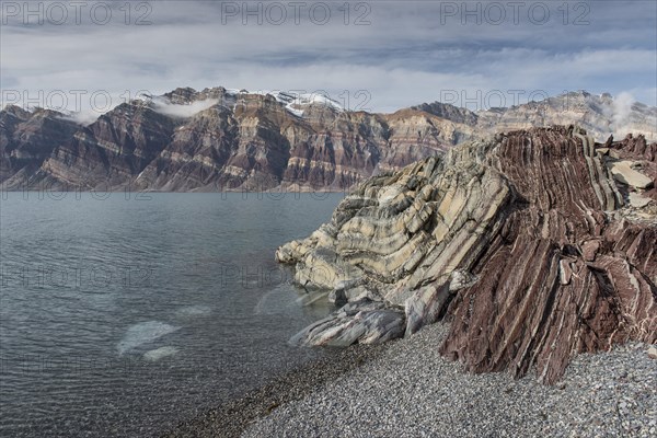 Stony beach and unfolded coloured rock strata