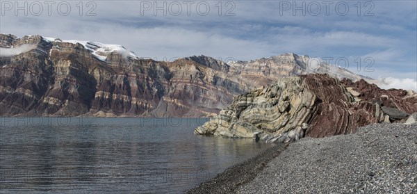 Stony beach and unfolded coloured rock strata