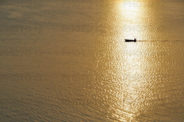 Fisherman in a motorboat at sunset