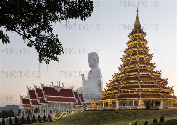 Illuminated Wat Huay Pla Kang temple at dusk with gigantic Guan Yin statue