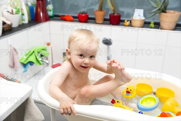 Toddler bathing in a bathtub for children with rubber ducks