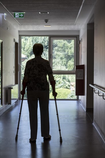 Elderly woman walking with crutches