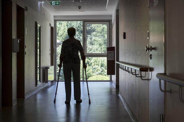 Elderly woman walking with crutches