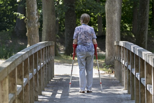 Elderly woman walking with crutches