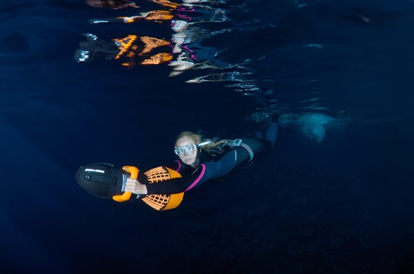 Freediver swimming with underwater scooter