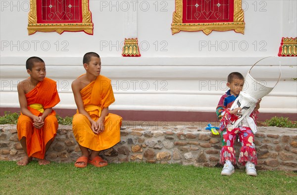 Two novices and a boy holding a mask