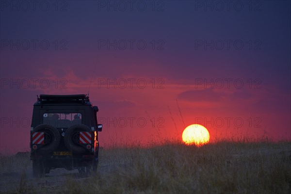 Jeep driving towards the setting sun