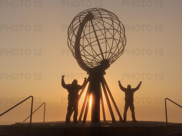 Two men next to the globe at the North Cape platform Nordkapplataet