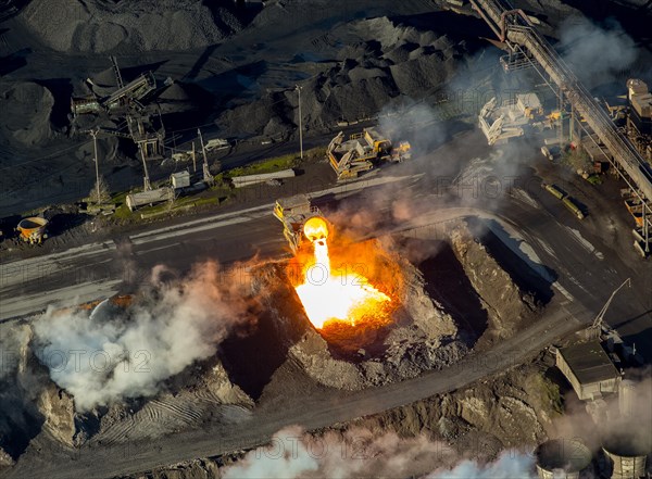 Glowing hot slag from iron production is tipped from a ladle car into a pit